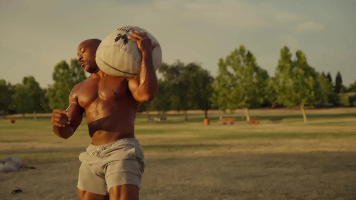 Nsima Inyang training outdoors with a sandbag on his shoulder
